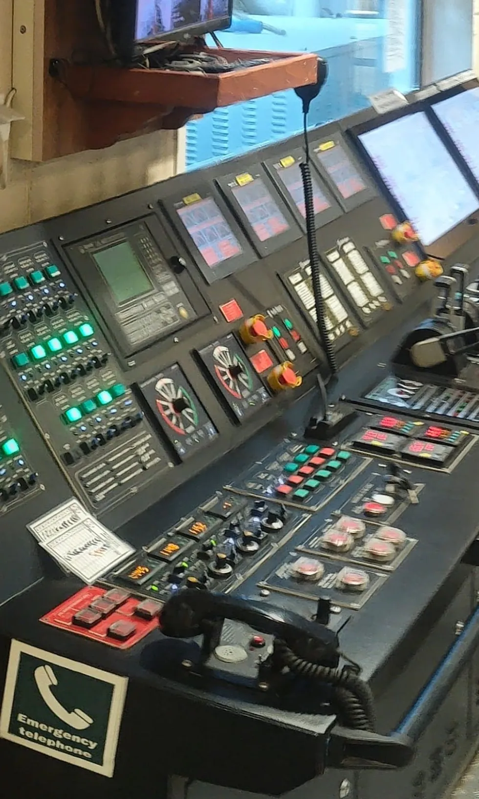 Makine kontrol odası konsolu: yanan sinyal butonları, alarm ekranları ve acil durum telefonu
